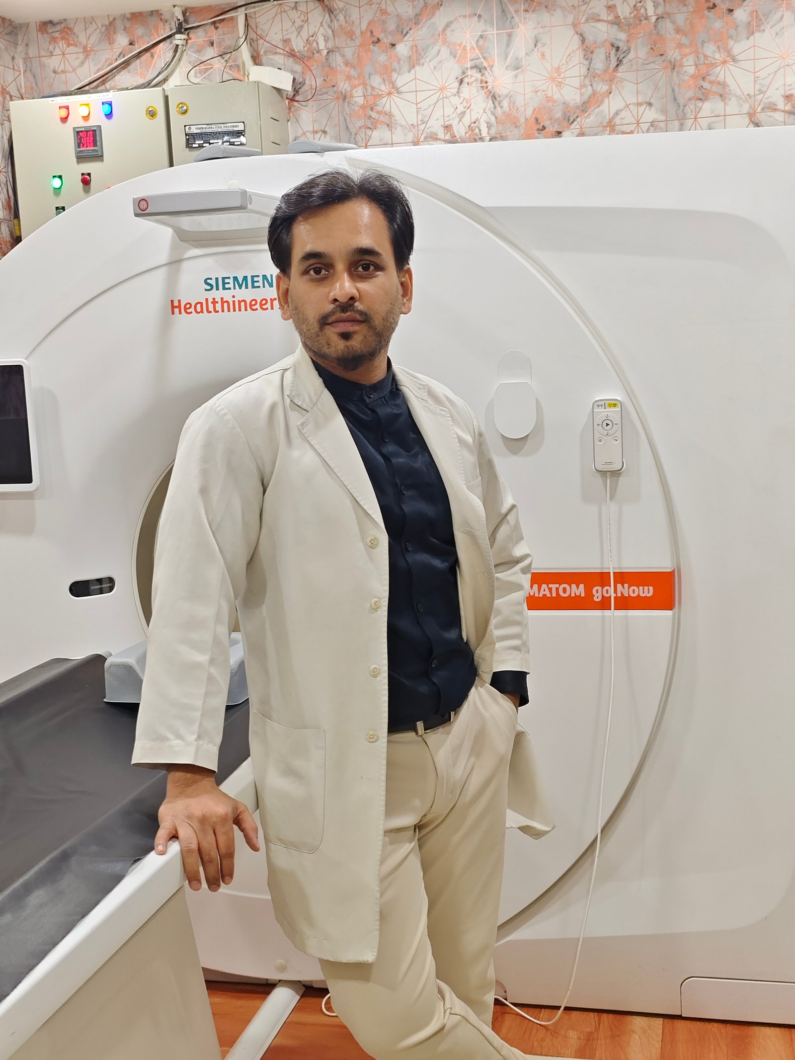 Dr. Manish Meshram beside the CT scanner
